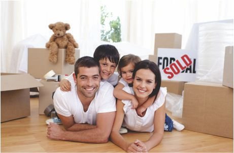 Una familia feliz de cuatro personas yace en el suelo rodeada de cajas de mudanza.